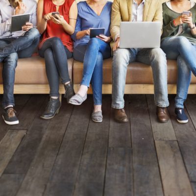 image of seven people, sitting, with devices or laptops