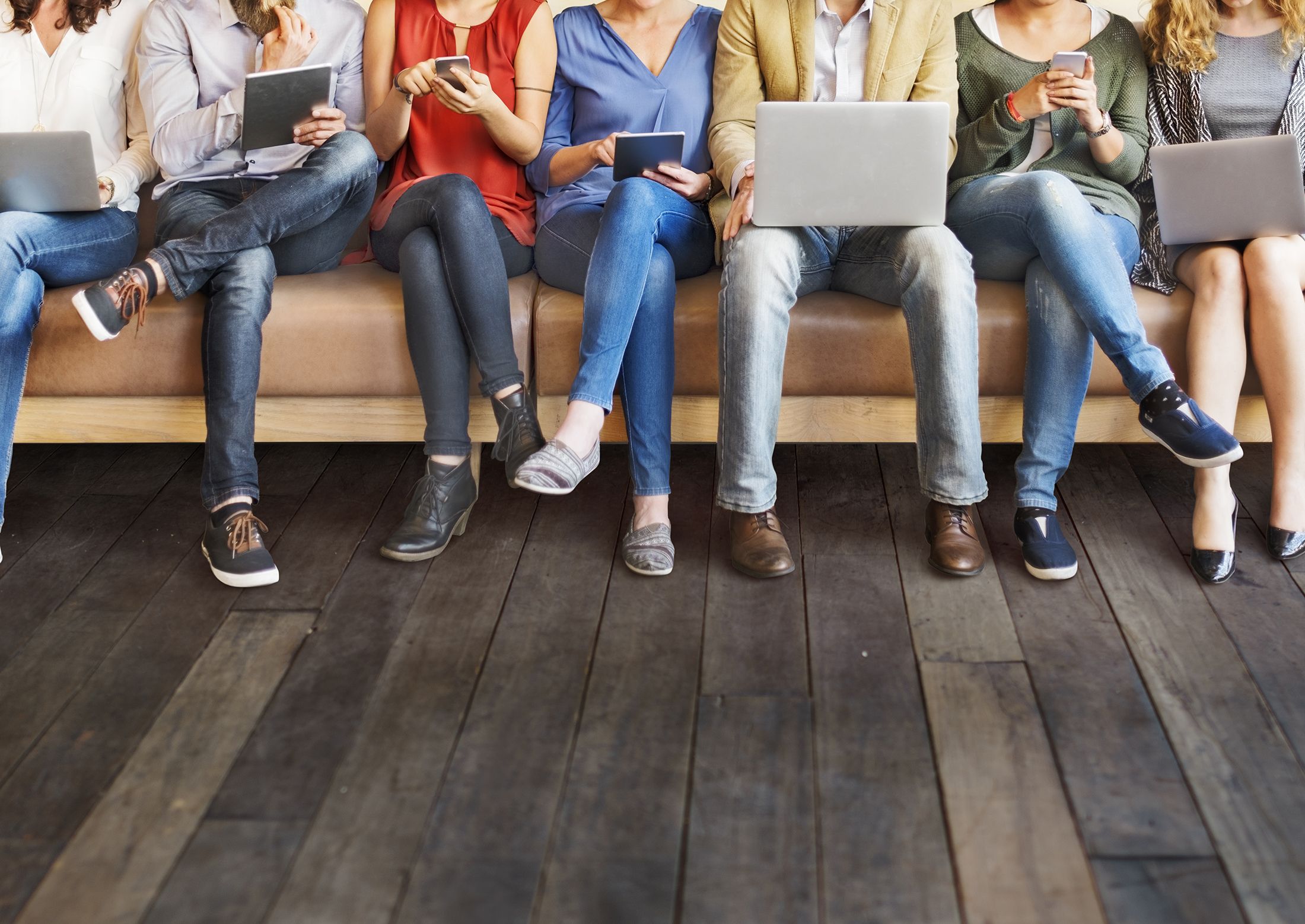 image of seven people, sitting, with devices or laptops